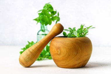 Hafif bir arka plan üzerinde ahşap bir harç yeşil limon fesleğen. Fesleğen şişe.