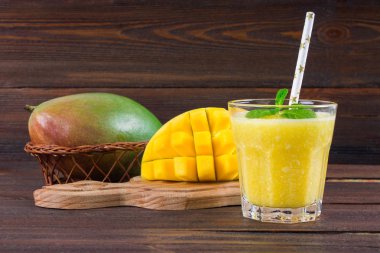 Saman ve nane bir cam ölçek ile smoothies mango. Dilimlenmiş mango ile plaka. Tropikal bir meyve. Ahşap arka plan