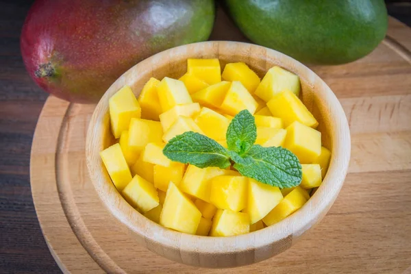 Tropical fruit mango in a plate on a wooden background, whole or — Stock Photo, Image