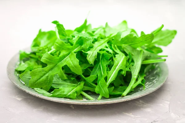 Folhas suculentas frescas de arugula em um fundo de concreto leve . — Fotografia de Stock