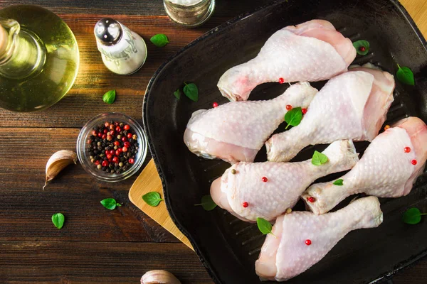 Ahşap bir masa üzerinde bir tavada çiğ tavuk budu. Et yemek pişirmek için malzemeler. Üstten Görünüm.