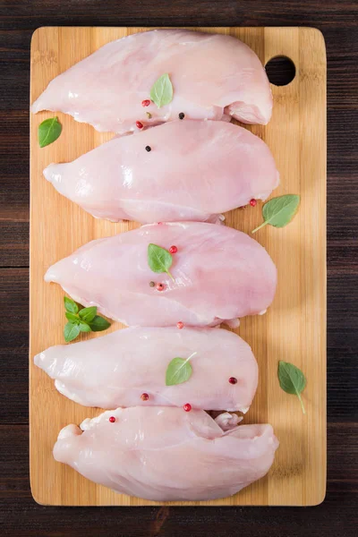 Çiğ tavuk fileto kesme tahtası ahşap bir masa arka planı. Et yemek pişirmek için malzemeler. Bir yazıt için boş yer. Uzay kopyalayın. Düz lei. Üstten Görünüm.