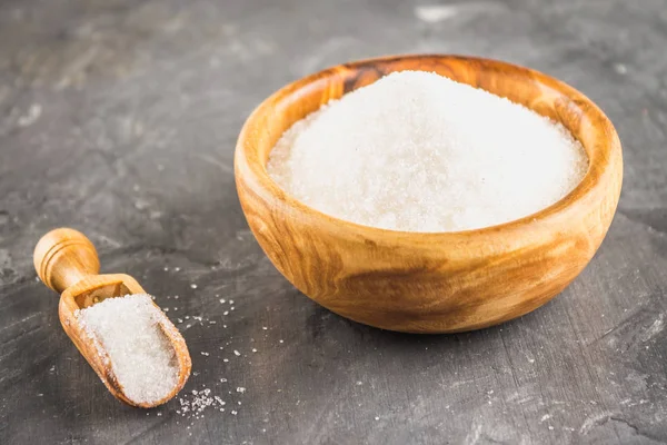 Açúcar branco açúcar em uma chapa de madeira com um pó em um fundo escuro . — Fotografia de Stock