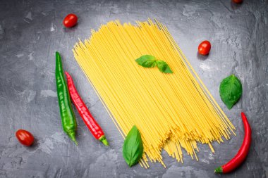 Domates, biber ve fesleğen üzerinde gri bir bac ile pişmemiş makarna