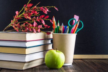 Öğretmenin gün kavramı. Bir kara tahta arka plan nesnelerinde. Kitap, yeşil elma, plak: mutlu öğretmenin gün, kalemler ve kalemler bir cam delikanlı ile sonbahar yaprakları.