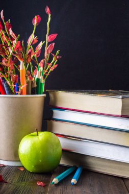 Öğretmenin gün kavramı. Bir kara tahta arka plan nesnelerinde. Kitap, yeşil elma, plak: mutlu öğretmenin gün, kalemler ve kalemler bir cam delikanlı ile sonbahar yaprakları.