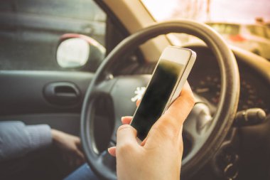 Kadın elinde telefon. Direksiyonun arkasında bir arabadaki kızla.