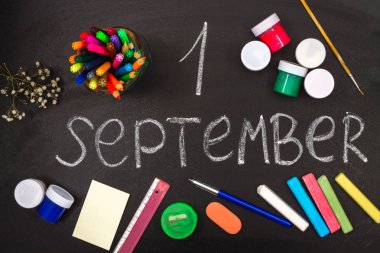 Yazıt Eylül 1'tır. Tebeşir ve okul malzemeleri bir kara tahta üzerinde çevrili.