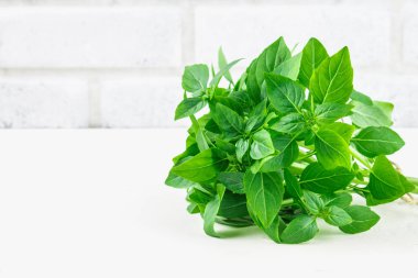 Bir tuğla duvar arka plan beyaz bir beton masada yeşil limon fesleğen demet