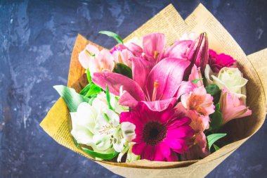 Buket çiçek lily, gerbera, beyaz gül ve alstroemeria koyu bir beton duvar arka planı. Bir tatil, bir hediye.