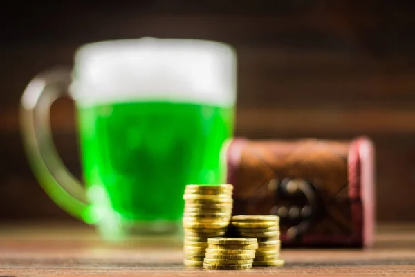 Ein Becher mit grünem Bier auf dem Tisch. Kleeblätter. Goldkiste, Münzen stapeln sich. St. Patrick 's Day. — Stockfoto