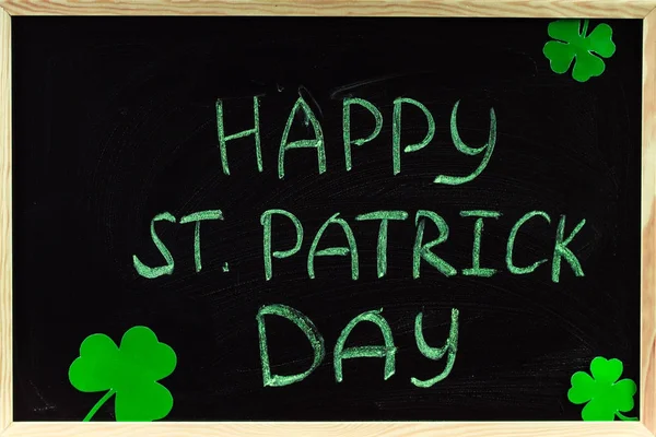 The inscription with green chalk on a chalkboard: Happy St. Patrick\'s Day. Clover leaves.