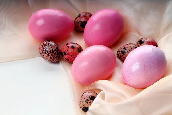 Розовые пасхальные яйца, лежащие на шелковой ткани — стоковое фото