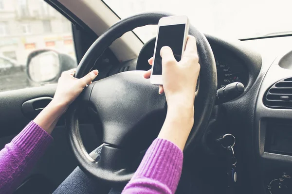 Telefon in den Händen von Frauen. Mädchen im Auto hinterm Steuer. — Stockfoto
