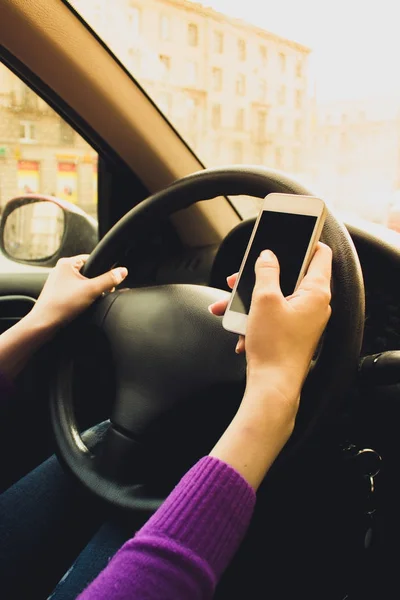 Telefon in den Händen von Frauen. Mädchen im Auto hinterm Steuer. — Stockfoto