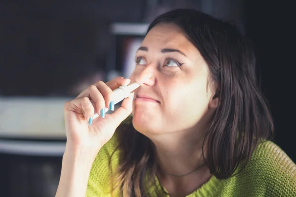 Het meisje maakt gebruik van een spray voor haar neus. Behandeling van verkoudheden, griep. — Stockfoto
