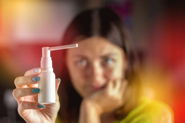 A rapariga está a considerar um spray para o nariz. Tratamento de constipações, gripe . — Fotografia de Stock