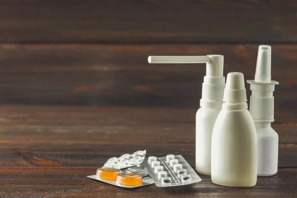 Aerosol nasal, gotas nasales, pastillas en la ampolla, caramelos de la tos en la mesa. Medicamentos modernos para resfriados, gripe. Tratamiento de la enfermedad . — Foto de Stock