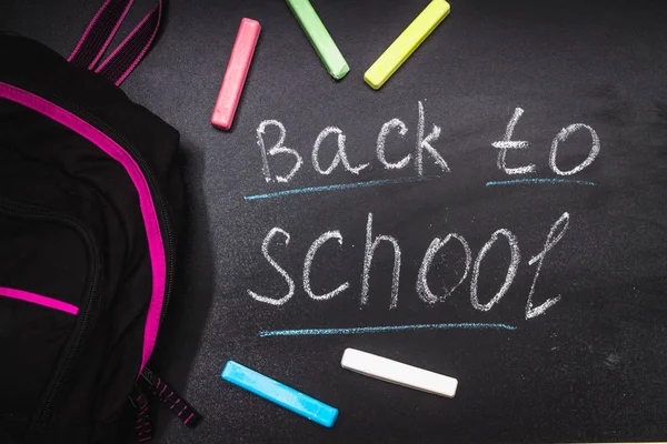 回到学校的信息黑板上刻着五颜六色的粉笔背景。背包. — 图库照片