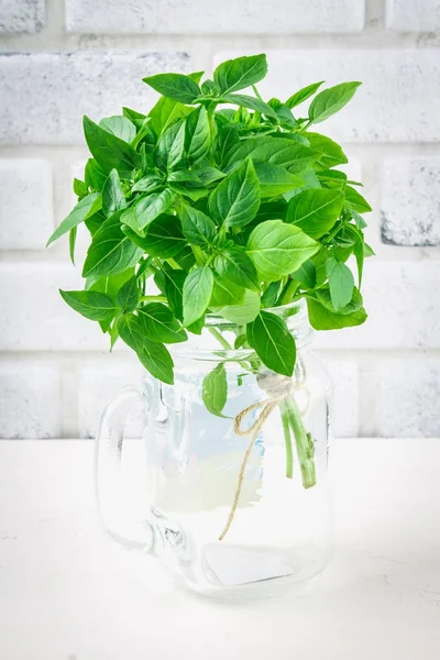 Um bando de manjericão limão verde em uma mesa de concreto branco contra um fundo de parede de tijolo — Fotografia de Stock