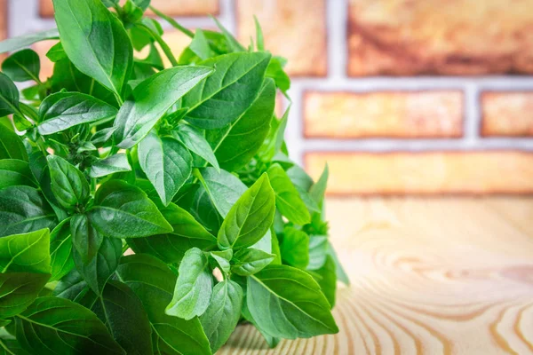 Yeşil limon fesleğen bir tuğla duvara kahverengi bir beton masada bir demet.