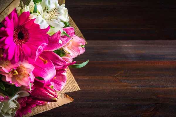 Un ramo de flores de lirio, gerberas, rosas blancas y alstroemeria sobre una mesa de madera marrón. Unas vacaciones, un regalo . — Foto de Stock