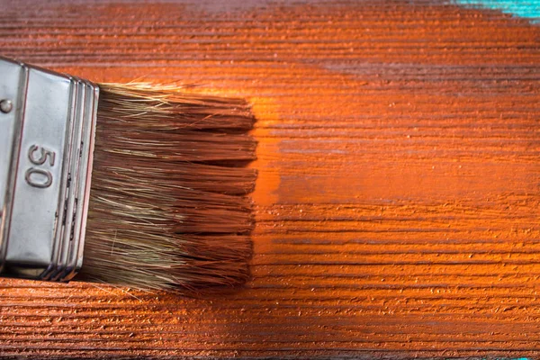 Brush with paint in hand. A man paints blue boards in a brown paint brush.