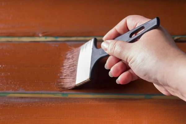 Escova com tinta na mão. Um homem pinta placas azuis em um pincel de tinta marrom . — Fotografia de Stock