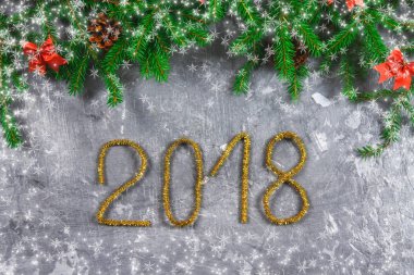 Çam dalları koniler ve gri beton zemin üzerine kırmızı yay ile. Yeni yıl Noel. Metin 2018 of altın gelin teli.