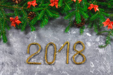 Çam dalları koniler ve gri beton zemin üzerine kırmızı yay ile. Yeni yıl Noel. Metin 2018 of altın gelin teli.