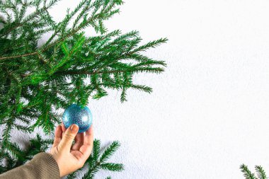 Bir Noel top beyaz zemin üzerinde bir Noel ağacı üzerinde asılı bir kız.