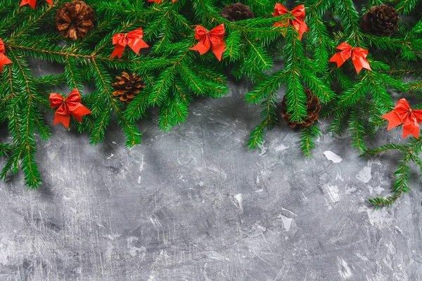 Ветки ели с конусами и красными луками на сером бетонном фоне. Новое Рождество. Свободное место для текста . — стоковое фото