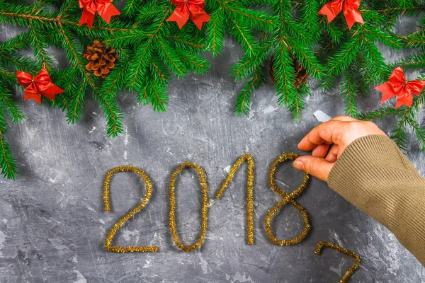 Ramas de abeto con conos y arcos rojos sobre un fondo de hormigón gris. Año Nuevo Navidad. Texto 2018 de oropel dorado . — Foto de Stock