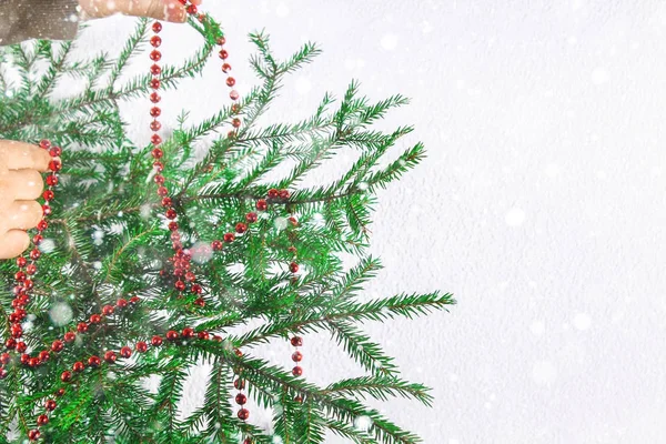 女孩垂悬新年红色小珠在一个白色背景的圣诞树上. — 图库照片