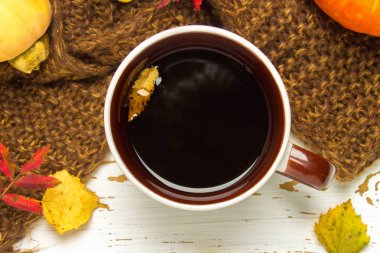 Örme bir eşarp ile ahşap bir masa üzerinde sonbahar ortamda sıcak kahve bir fincan kazak. Konfor, sıcaklık, rahat.