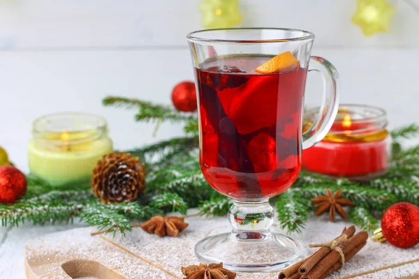 Πρωτοχρονιάτικο mulled κρασί σε ποτήρι στο φόντο, κλαδιά, κεριά και στεφάνια και. — Φωτογραφία Αρχείου