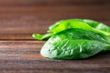 Ahşap bir masa üzerinde yeşil taze ıspanak yaprakları.