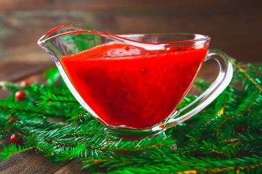 Fuska kızılcık sosuna çam dalları ile ahşap bir masa üzerinde bir cam temiz daire.