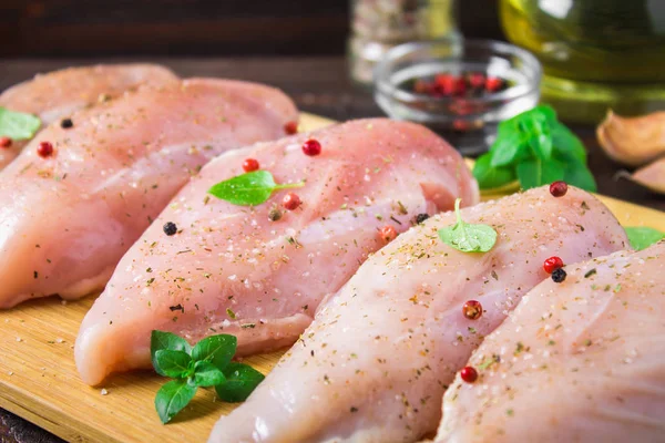Raw chicken fillets on a cutting board against the background of a wooden table. Meat ingredients for cooking.