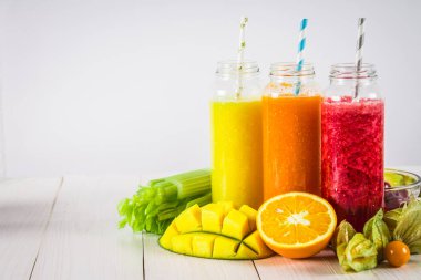 Mango, portakal, muz, kereviz, çilek, ahşap bir masa üzerinde şişelerde çok renkli smoothies.