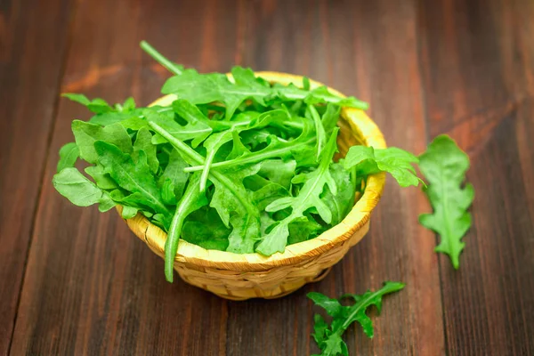Fresh juicy leaves of arugula on a brown wooden table. — Stock Photo, Image