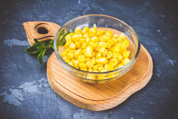 Canned corn in a glass plate on a gray concrete background. — Stock Photo, Image