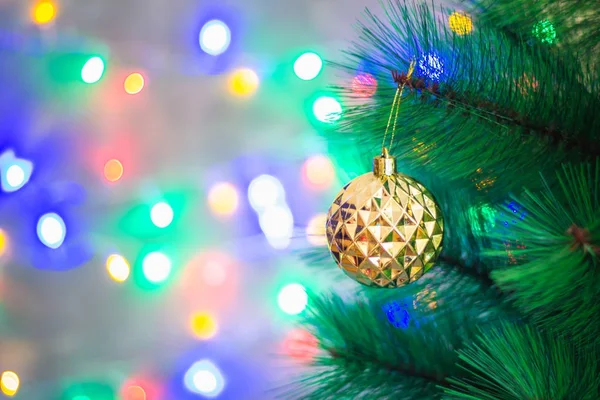 Palla d'oro di Natale su un albero di Natale su uno sfondo di scintille di ghirlande, bokeh . — Foto Stock