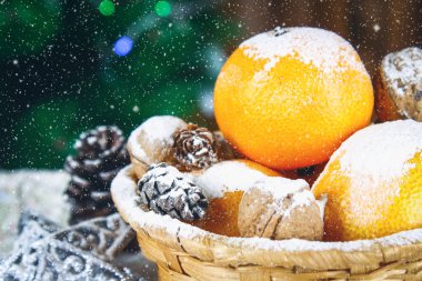 Mandalina, ceviz ve çarpmak bir Noel ağacı arka plan üzerinde bir sepet içinde.