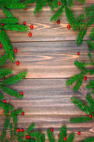 Las ramas de abeto con bayas rojas en una mesa de madera. espacio de copia . — Foto de Stock