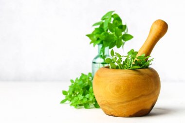 Hafif bir arka plan üzerinde ahşap bir harç yeşil limon fesleğen. Fesleğen şişe.