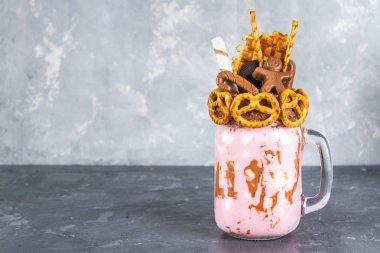 Pembe yüzlü, krem üzerinden Freakshake. Çikolata bir adam, bastonu, kraker, bisküvi, waffle ve hatmi ile Monstershake. Bir Mason kavanoza aşırı milkshake. Koyu gri beton arka plan.