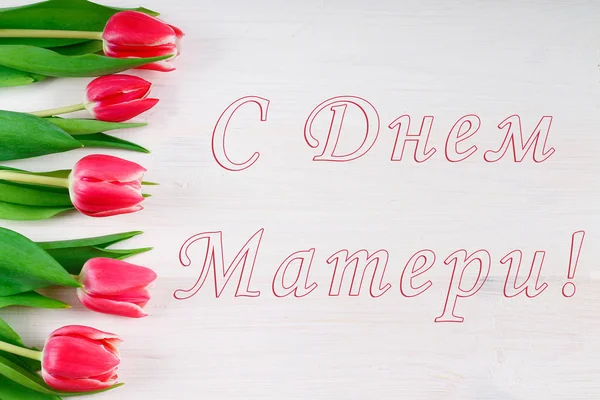 Różowe tulipany na biały drewniany stół z napisem w języku rosyjskim - Happy Mother's Day. — Zdjęcie stockowe