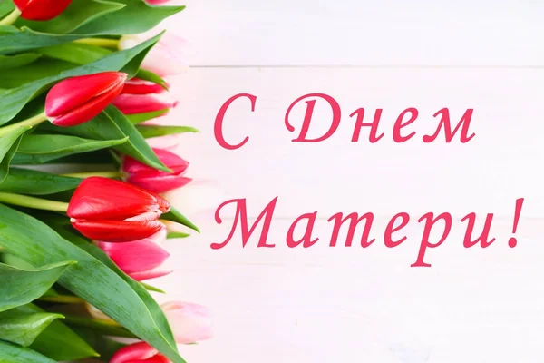 Różowe tulipany na biały drewniany stół z napisem w języku rosyjskim - Happy Mother's Day. — Zdjęcie stockowe