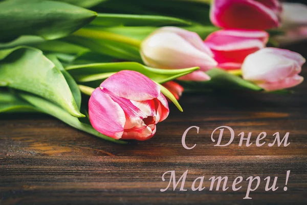 Różowe tulipany na drewniany stół z napisem w języku rosyjskim - Happy Mother's Day — Zdjęcie stockowe
